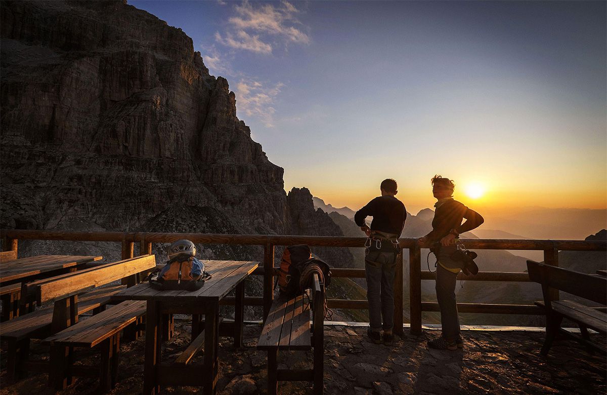 2 Meschen genießen den Sonnenuntergang am Gardasee auf der Terrasse des Hotels BAIA AZZURRA in Torbole