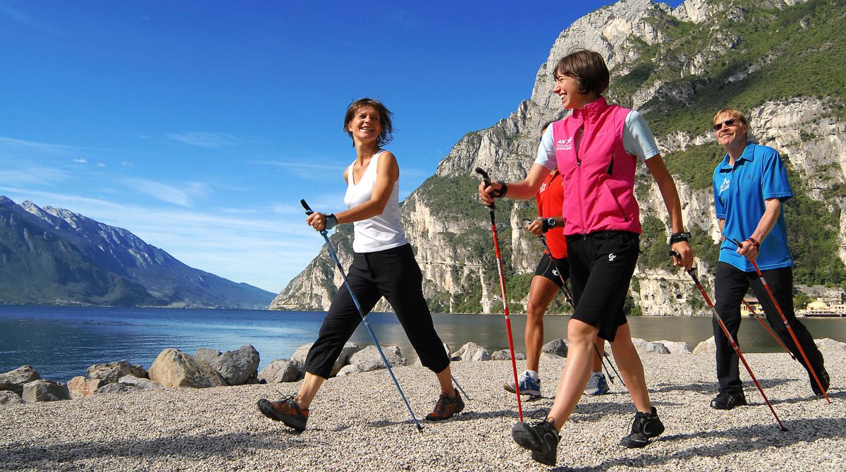 4 Personen machen Nordic Walking am Strand von Torbole am Gardasee in Italien